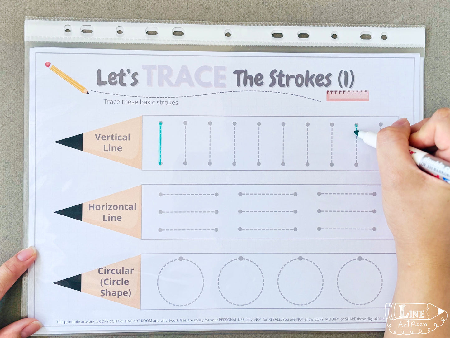 Hand holding a marker tracing lines on a educational worksheet titled 'Let's Trace the Strokes'.